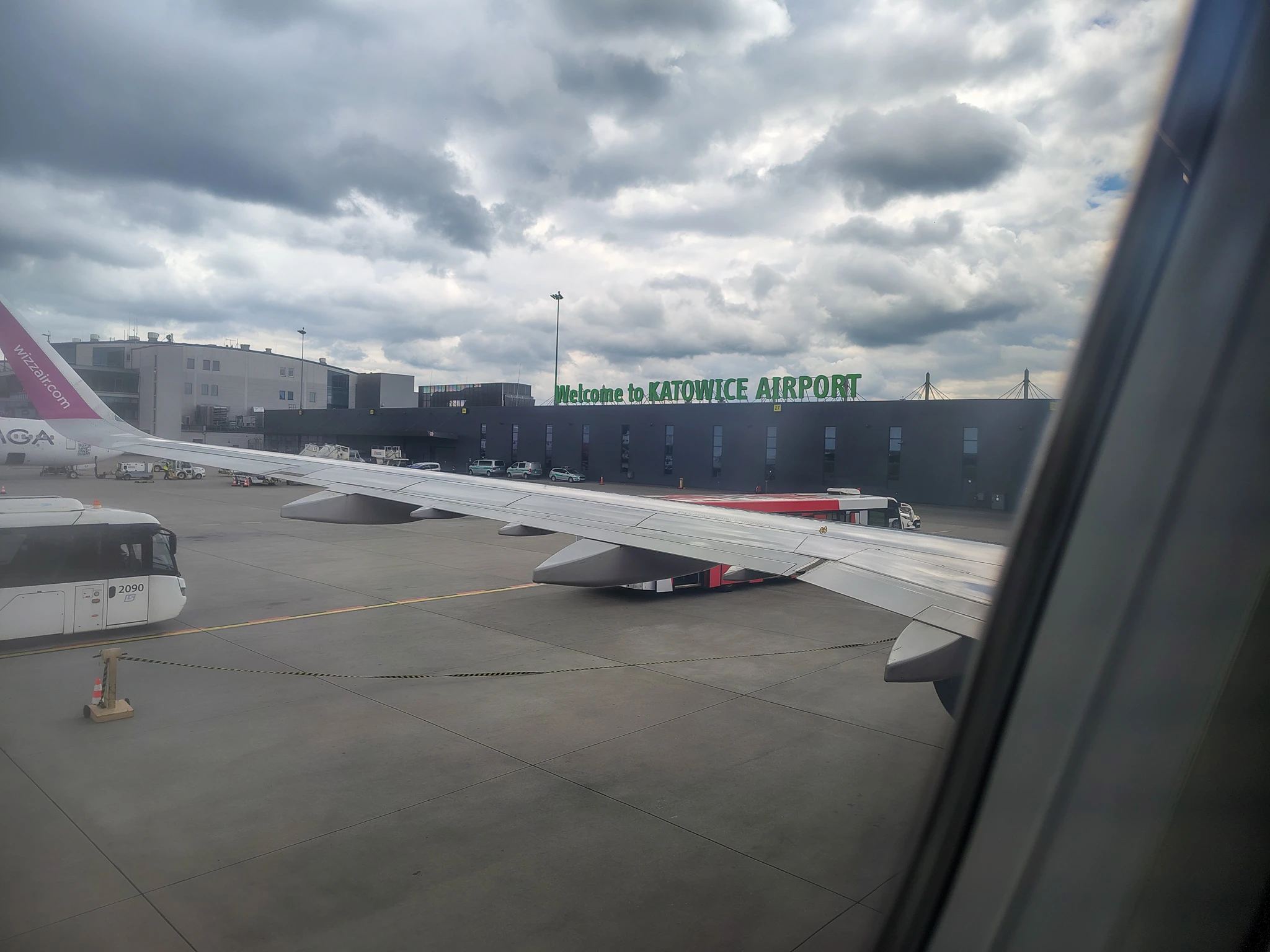 Terminal B lotniska Katowice Pyrzowice (KTW) z nowoczesną szklaną fasadą, przejściem dla pieszych i pasażerami. Idealny punkt wylotów Ryanair.